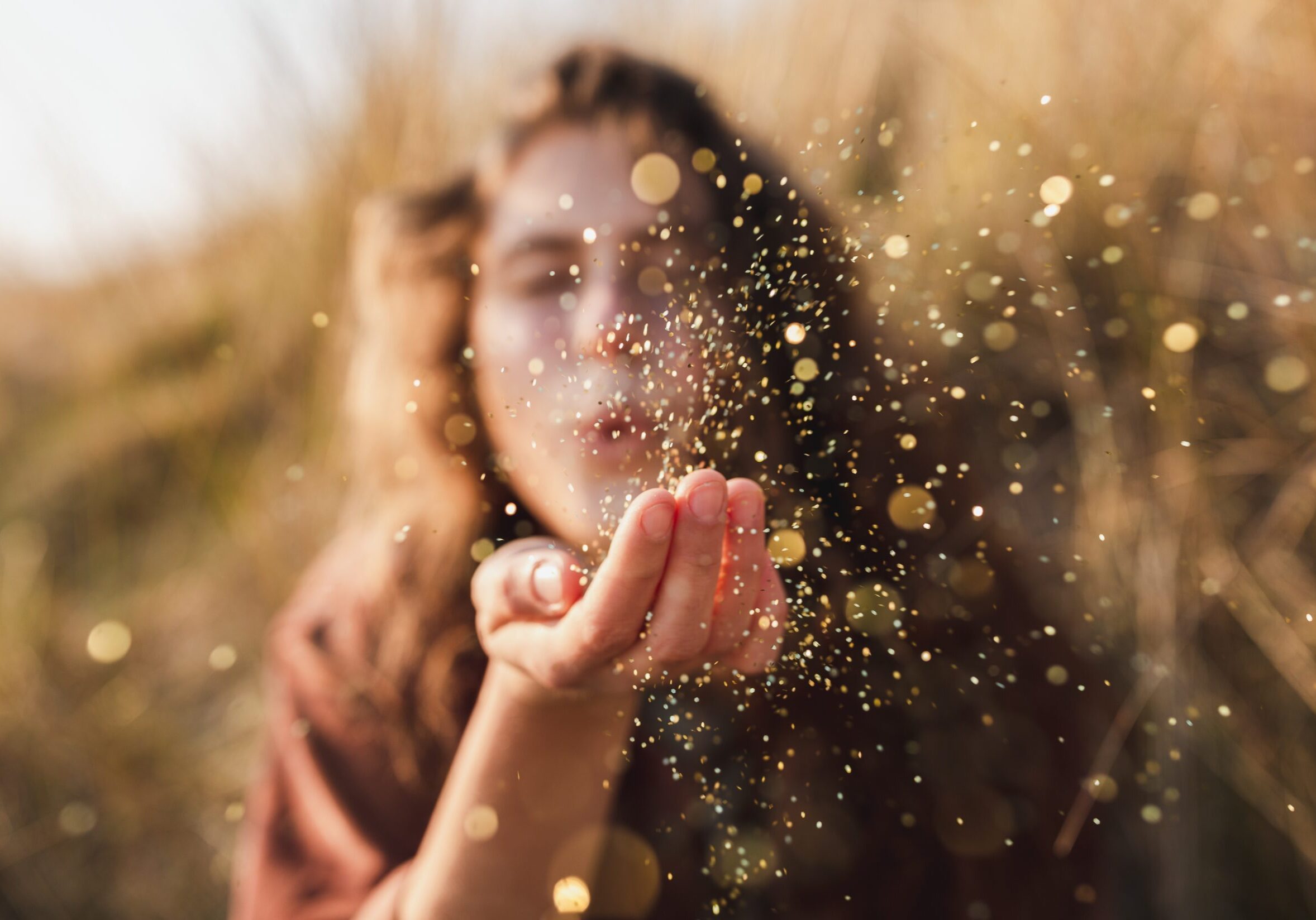 Beautiful shot of a model blowing glitter from her hand A beautiful shot of a model blowing glitter from her hand